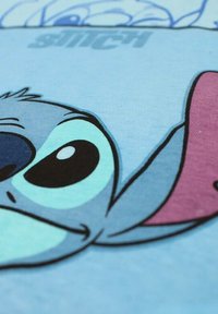 Tissu bleu présentant un graphisme détaillé d'un personnage de dessin animé aux grands yeux noirs, illustré en nuances de bleu et de violet.