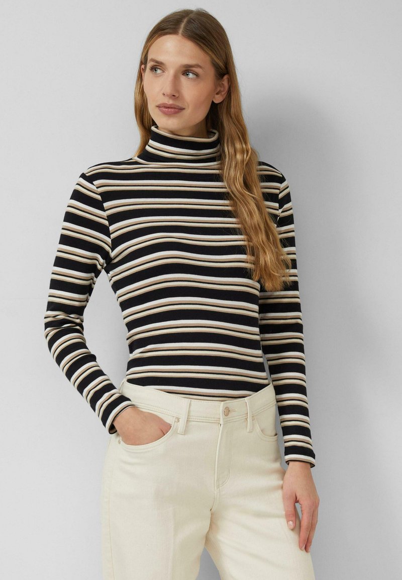 Golf w czarno-kremowe paski z długimi rękawami, wykonany z lekkiego materiału, zestawiony z jasnymi dżinsami, prezentowany na neutralnym tle.