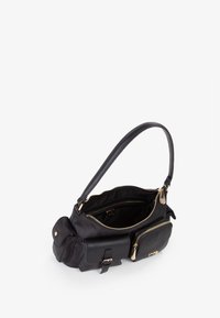 Borsa nera realizzata in tessuto liscio, dotata di un singolo manico, scomparto principale con zip e tasche esterne con dettagli in metallo dorato.