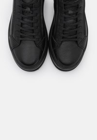 Mustat nahkaiset korkeavartiset tennarit, joissa on tekstuuripinta, pyöreät nauhat, pyöreä kärki ja hienovaraiset ommeltut yksityiskohdat päällisessä.