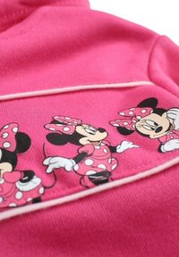 Sweat à capuche rose avec une impression graphique de Minnie Mouse dans diverses poses, orné de pois et d'une bordure contrastante. Texture lisse.