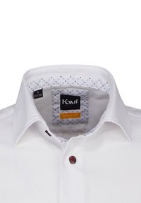 Camicia bianca con bottoni a corsetto dal taglio moderno. I dettagli del colletto includono un motivo geometrico con accenti blu e rossi. Singolo bottone color marone.