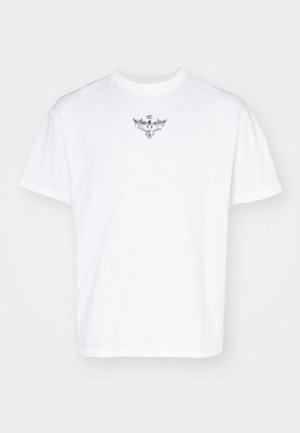 Biała bawełniana koszulka z okrągłym dekoltem, luźnym krojem i srebrnym wzorem graficznym przedstawiającym skrzydła na klatce piersiowej.