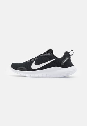 Svart träningsskor med meshuppbyggnad, vit Nike-swoosh och vit sula. Har strukturerad design, snörning och hälflik för enkel påtagning.
