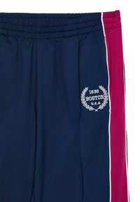 Navyblaue Trainingshose mit rosa seitlichen Einsätzen. Sie verfügt über einen elastischen Bund und ein weißes, gesticktes "BOSTON 1636 U.S.A."-Logo mit Lorbeerdesign.