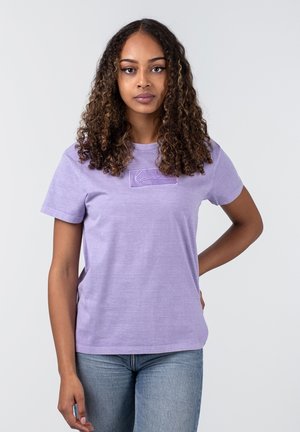 Lilla bomulds t-shirt med korte ærmer, rund hals, der har et struktureret broderet design på forsiden. Flad kant og afslappet pasform.