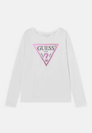 Chemise blanche à manches longues avec un logo triangulaire rose affichant "GUESS U.S.A." et un point d'interrogation au centre.
