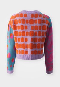 Lila stickad tröja med orange rundad fyrkantmönster på ryggen, turkos ärm med orange och rosa cirklar samt rosa ärm med blå abstrakta former.