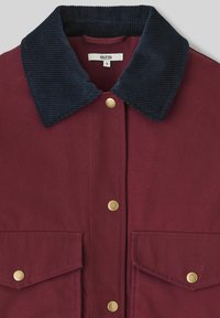 Veste bordeaux avec un col en velours côtelé bleu marine, ornée de boutons pression dorés et de deux poches avant, fabriquée dans un tissu à la texture lisse.