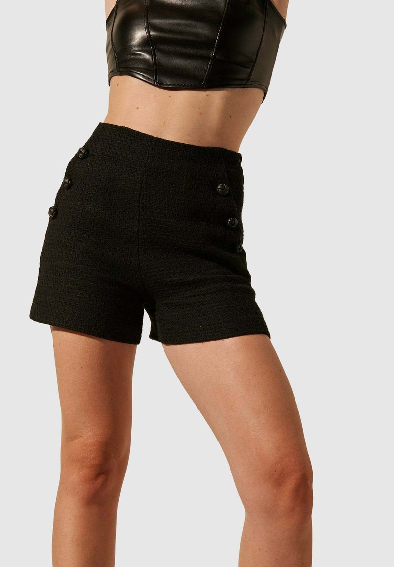 Shorts noirs texturés avec une taille haute et cinq boutons décoratifs noirs à l'avant. Conçus pour une silhouette ajustée.