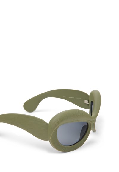 Zelené sluneční brýle s oversized, kulatým rámem, texturovaným povrchem a tmavými skly. Mají široké, zakřivené nožičky pro pohodlné nošení.