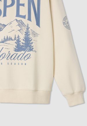 Beżowy sweatshirt z napisem "ASPEN" w niebieskim kolorze, grafiką gór, zielonymi drzewami iglastymi oraz prążkowanymi mankietami i dołem.