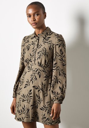 Bruine bloemenjurk met lange pofmouwen, een knoopsluiting bij de kraag en een getailleerde taille. Heeft een zwart loofpatroon op een beige achtergrond.