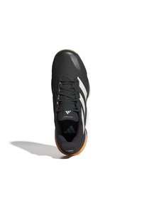 Scarpa sportiva nera con tomaia testurizzata, caratterizzata da tre strisce bianche, dettagli dorati e una suola multicolore che sfuma dal nero all'arancione.