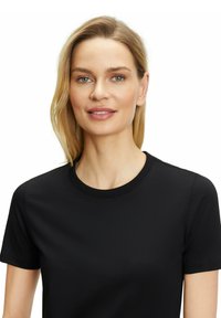 Czarny, krótki t-shirt z miękkiego materiału, z okrągłym dekoltem. Gładka faktura, minimalistyczny design, bez widocznych wzorów czy akcentów.