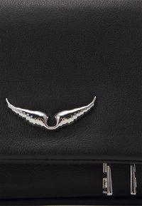 Zwarte leren handtas met een zilverkleurig vleugelvormig embleem en verfijnde metalen accenten, met een gestructureerd oppervlak en strakke lijnen.