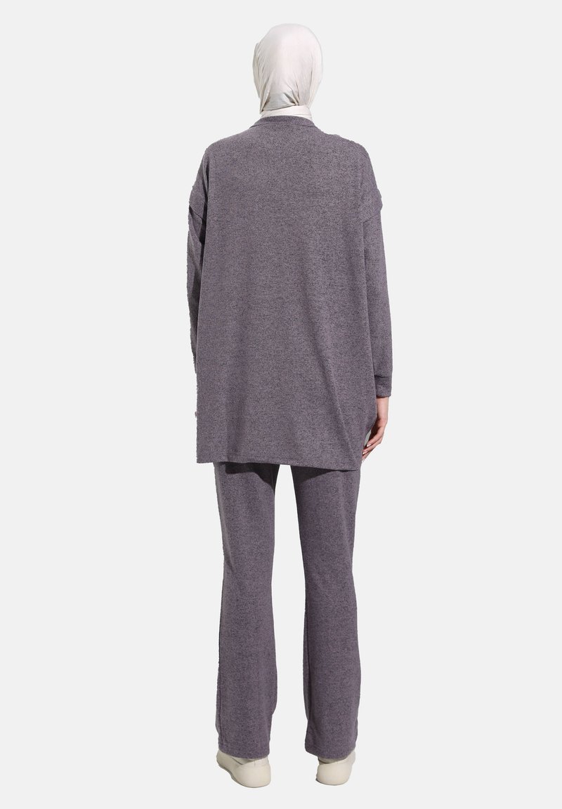 Ensemble deux pièces gris composé d'une tunique longue et d'un pantalon fuselé, avec une texture douce et une coupe décontractée. Complété par un hijab blanc.