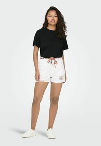 Black short-sleeve t-shirt paired with white shorts featuring a colorful drawstring and distressed accents. Worn with white sneakers.