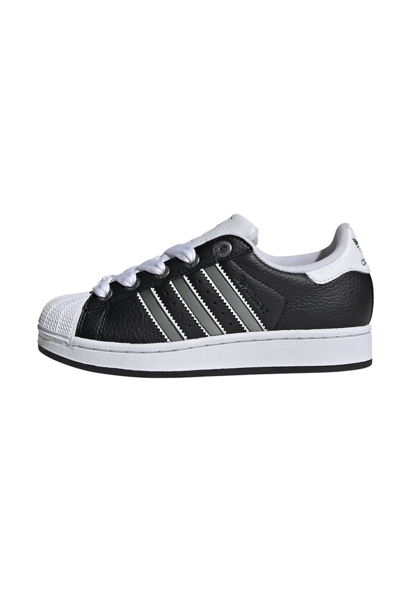 Black and white sneaker with a leather upper, rubber toe cap, three grey stripes on the side, and white laces. Flat sole design.