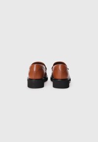 Chaussures en cuir marron avec un bout arrondi et un petit talon noir. Texture lisse avec des coutures discrètes à l'arrière.