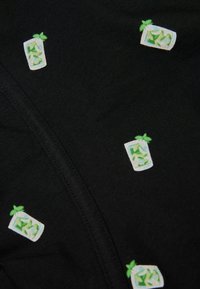 Černá látka s malými vyšívanými motivy zelené máty a nápojů. Design zahrnuje bílé šálky se zelenými akcenty.