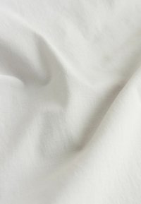 Fehér anyag sima textúrával és diszkrét függőleges csíkokkal, enyhe gyűrődéssel és puha, könnyű megjelenéssel.