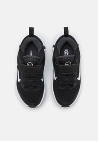 Zwarte sportieve schoenen met een bovenwerk van mesh, witte accenten en een verstelbare riem. Dit model heeft een ronde neus en een gestructureerde zool voor grip.