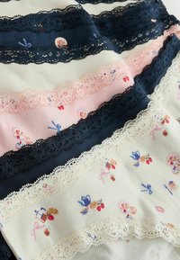 Stos damskiej bielizny z koronkową lamówką w kolorach granatowym, różowym i kremowym, z małymi nadrukami kokardek, imbryków i ciast.