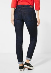Mörkblå denim skinny jeans med en slät yta, försedda med nedrullade fållar och bakfickor. Kompletterade med en enfärgad midjebandsetikett.