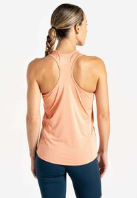 Ein hellpeachfarbener Sporttanktop mit Racerback-Design, kombiniert mit dunkelblauen Leggings. Der Stoff scheint glatt mit einer subtilen Textur zu sein.