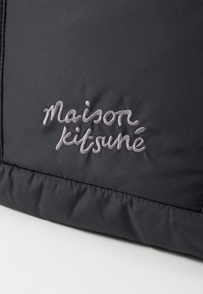 Black puffer jacket featuring quilted texture and embroidered "Maison Kitsuné" logo in light gray on the fabric.