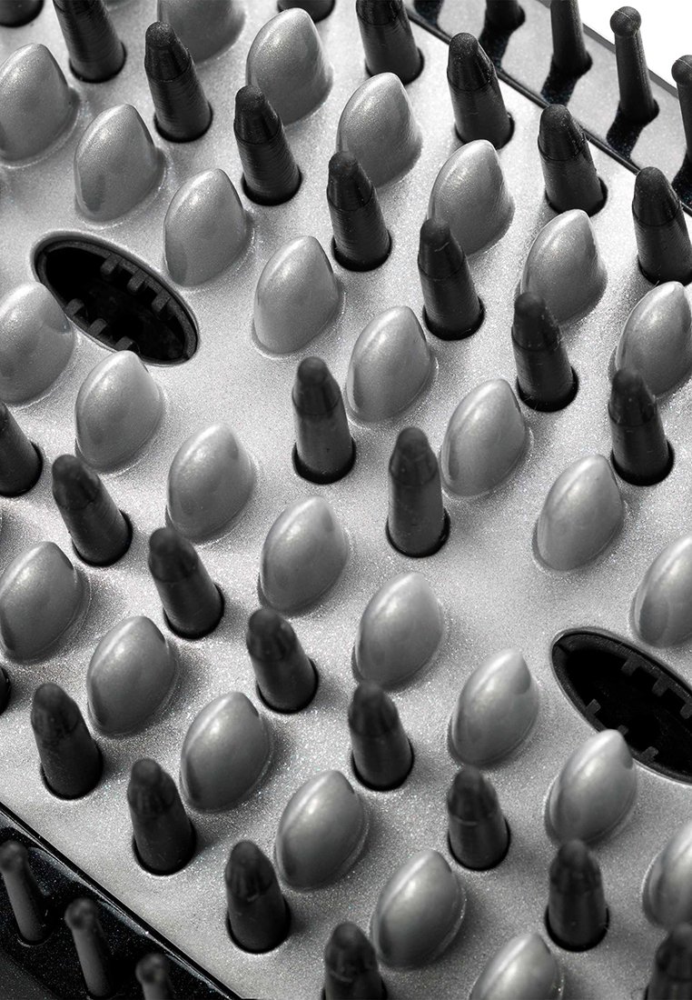 Graue und schwarze Gummimatte mit hervortretenden, runden Stiften, die in einem Rastermuster angeordnet sind, und einem zentralen Öffnung für Funktionalität.