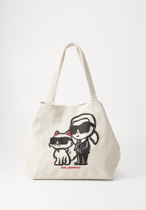 Beżowa torba na ramię z rysunkiem mężczyzny w okularach przeciwsłonecznych i garniturze stojącego obok kota również noszącego okulary przeciwsłoneczne, poniżej napis "Karl Lagerfeld".