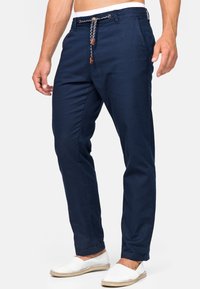Pantalones ligeros azul marino con cintura ajustable, con acentos marrones, piernas ajustadas y bolsillos laterales. Textura suave y diseño casual.