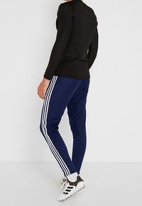 Black long-sleeve top paired with navy blue athletic pants featuring white stripes along the sides and black decorative accents.
