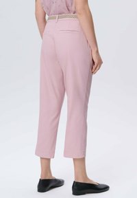 Jasnoróżowe, krótkie spodnie z plecionym beżowym paskiem, posiadające dwie tylne kieszenie i gładką teksturę. Noszone z czarnymi balerinami.