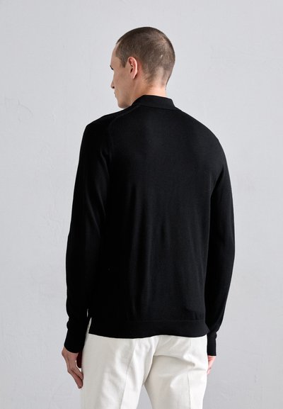 Sort sweater med lange ærmer og et enkelt design, der har en ribbet tekstur og rund hals. Bagsiden viser sømløse skuldrer og en ren pasform.