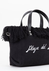 Borsa nera intrecciata con frange nella parte superiore, doppi manici in pelle nera e testo ricamato bianco "Playa del". Presenta un tessuto testurizzato.