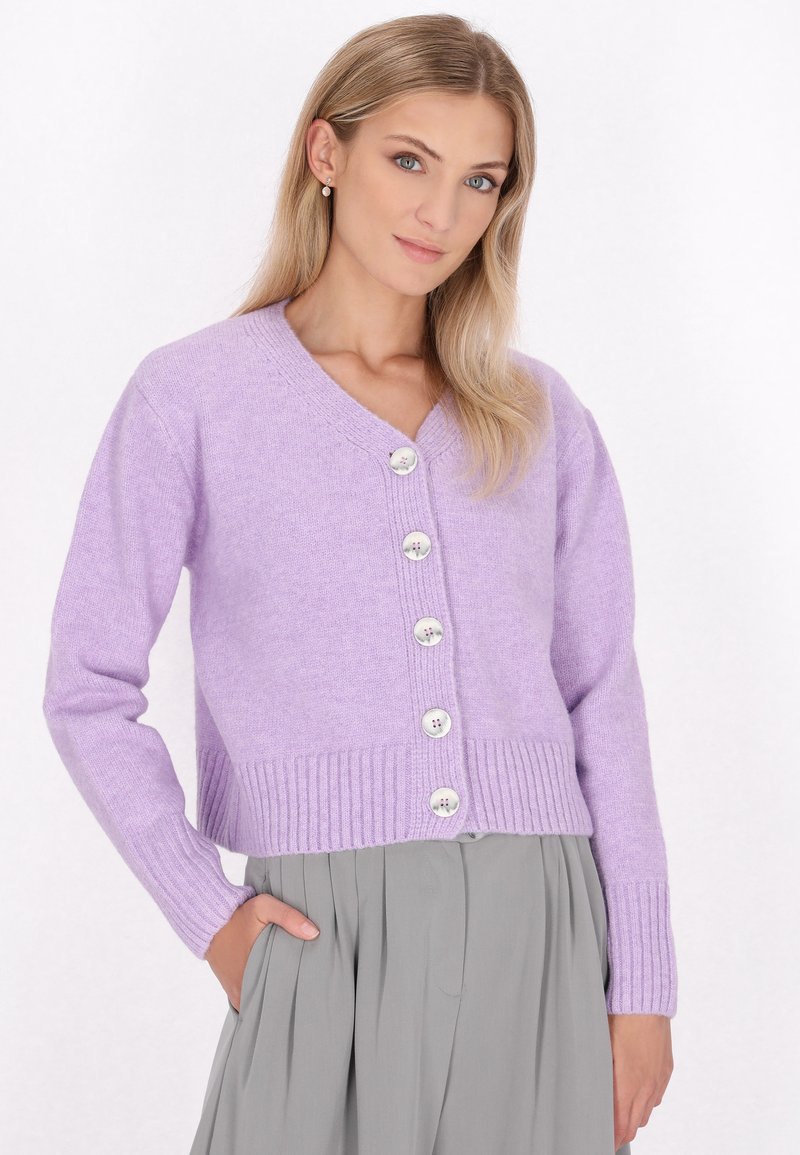 Levandulový pletený cardigan s výstřihem do V, žebrovaným lemem a pěti velkými, kontrastními knoflíky. Měkká textura a uvolněný střih.