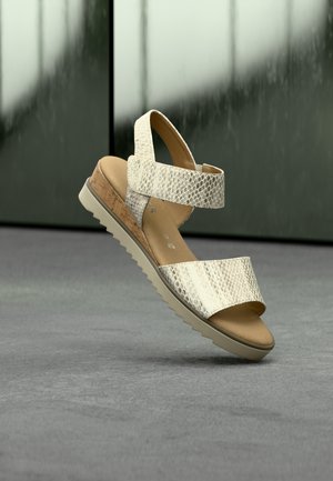 Lysebeige sandaler med kunstig slangeskindstruktur, to brede stropper, kork-mellemsål og en tekstureret gummisål, vist mod en neutral baggrund.