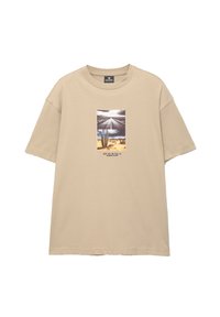 Beige bomulds T-shirt med korte ærmer, der har et centralt grafisk motiv af en ørkenscene med en kaktus og en vej, suppleret med tekst nedenfor.
