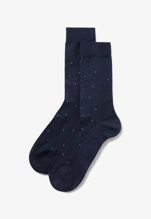Marineblaue Socken bis zur Mitte der Wade mit kleinem, mehrfarbigem Punktmuster und gerippten Bündchen, flach nebeneinander ausgelegt.