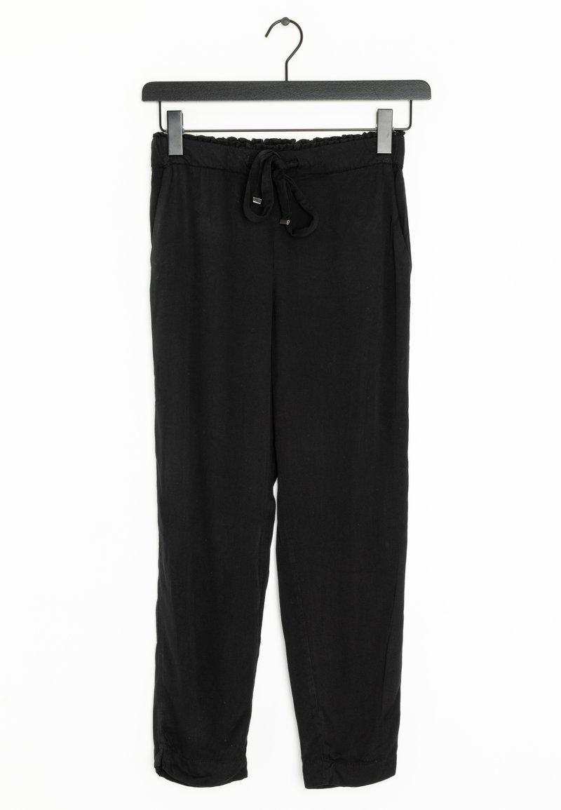 Černé joggingové kalhoty visící na černém ramínku. Mají elastický pas se šňůrkou, hladkou texturu a zúžený střih nohou.