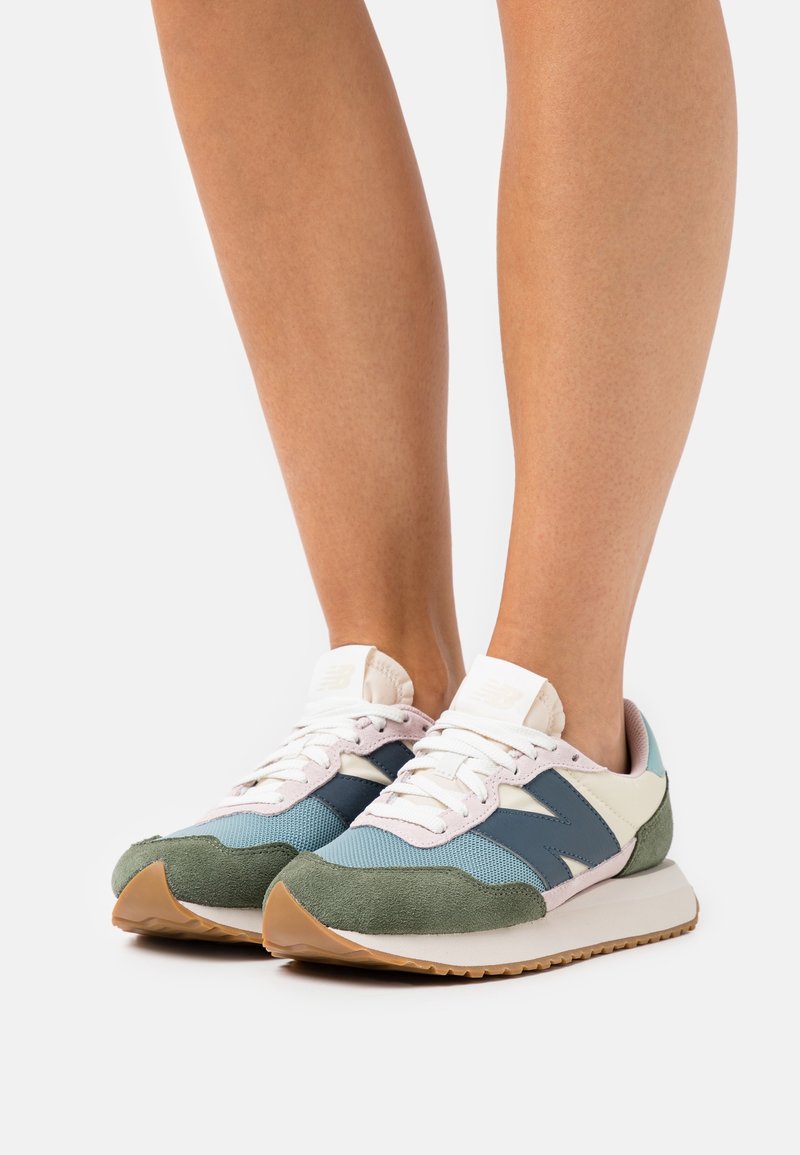 Sneakers med en grön mockafront, pastellblåt nät, marinblå sidopaneler och ljusrosa detaljer. Vita snören och gummisula.