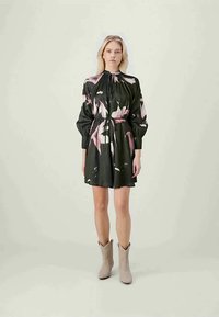 Vestido preto com estampa floral, mangas longas bufantes, decote franzido e um laço ajustável na cintura. Tecido suave com um leve brilho.