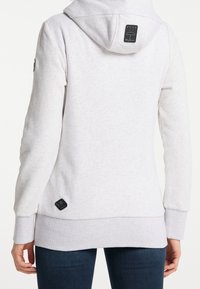 Světlá šedá mikina s klokankou, nastavitelnými šňůrkami a černým logem značky na zadní části a spodním lemu. Měkká textilie.