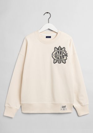 Kremfarvet sweatshirt med rund hals, der har et sort broderet logo på brystet og en vævet label nederst til venstre.