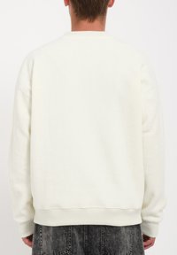 Sweatshirt blanc en tissu texturé, avec un col rond et des poignets et un ourlet côtelés. Présente une coupe décontractée et un design uni sans motifs.