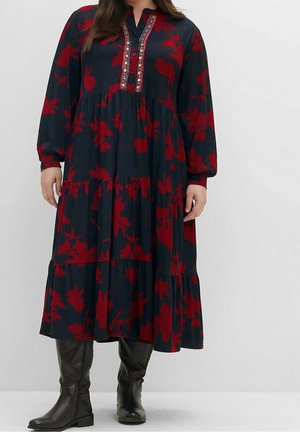 Mujer con vestido midi azul oscuro con estampado floral rojo, mangas largas, escote decorativo con botones y botas negras hasta la rodilla.