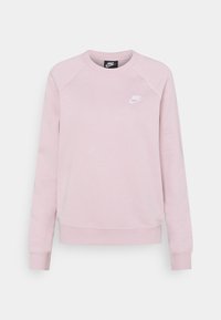 Rosa Nike-tröja med långa raglanärmar, ribbade muddar och fåll. Har en liten vit logotyp på vänstra bröstområdet. Mjuk textur.